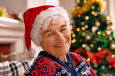 Christmas is always the best time of year. A senior woman sitting inside wearing a Christmas hat.