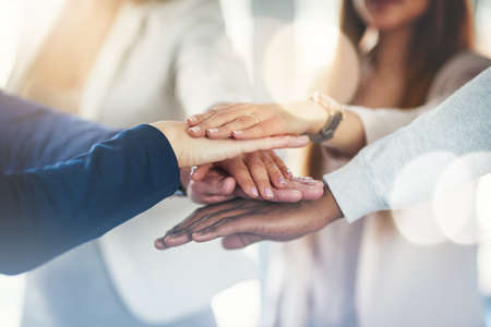 Lets do it together. Cropped shot of a group of businesspeople putting their hands together in a...
