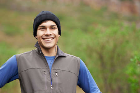 Outdoor training is the only way to go. A handsome young trail runner smiling widely after an...