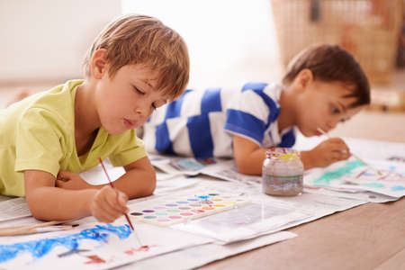 Unleashing their inner artists. Shot of two young boys painting pictures at home.の写真素材
