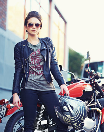 Riding with an attitude. Shot of a young and stylish female motorcycle rider outside.の写真素材