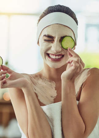 Its both cooling and purifying for my skin. Shot of an attractive young woman holding cucumber slices in front of her eyes.の写真素材
