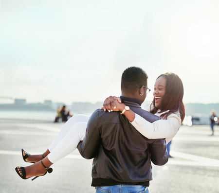 And just like that he swept her off her feet. Shot of an affectionate young couple bonding together outdoors.の写真素材