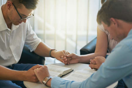 Were praying that success comes along our way. Shot of a group of young businesspeople holding hands while deep in prayer at work.の写真素材