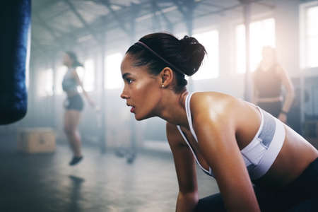Eyes on the prize, giving up is never an option. Cropped shot of a focused young sportswoman in the gym sitting down and taking a break.の写真素材