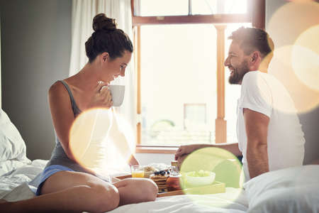 Its the little things that make life great. Cropped shot of a happy young couple enjoying breakfast in bed together at home.の写真素材