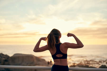 The habit of persistence is the habit of victory. Shot of a young sporty woman flexing after her workout.の写真素材