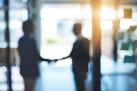 Lets call it a deal. Defocused shot of two businesspeople shaking hands in an office.