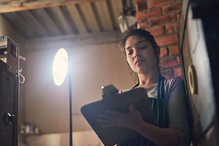 Shes got quite a few orders to process. Shot of a young entrepreneur writing on a clipboard in a...