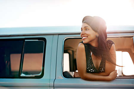 Off to see whats out there. Shot of a happy young woman leaning out of the window during a road...