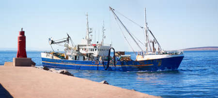 First catch of the day. Shot of a fishing trawler leaving the harbour.