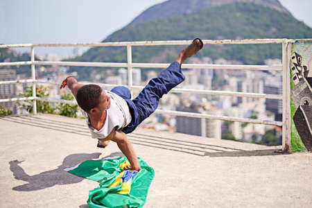 Performing in the streets of Brazil. Shot of a young male breakdancer in an urban setting.の写真素材