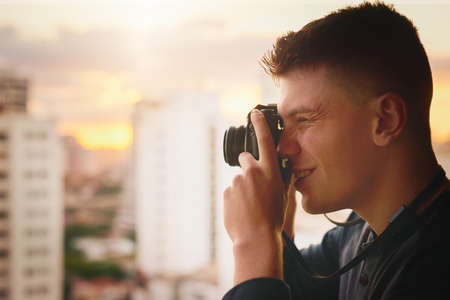 Trying to capture that perfect shot from this perfect spot. Cropped shot of a young man taking photographs of the city with a camera outside.の写真素材