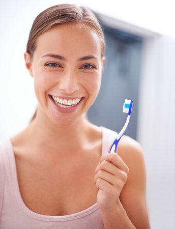 Taking care of her smile. A young woman brushing her teeth.の写真素材
