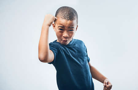 These guns are growing by the day. Studio shot of a cute little boy flexing his muscles against a grey background.の写真素材