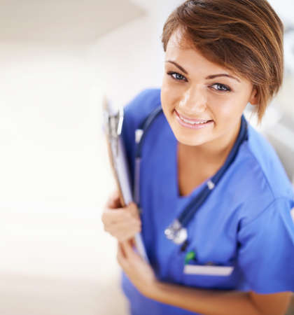 Making sure youre healthy keeps her happy. Portrait of an attractive young doctor in scrubs holding a clipboard.の写真素材