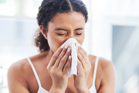 Just a little case of the sniffles. Cropped shot of an attractive young woman blowing her nose in the bathroom at home.の写真素材