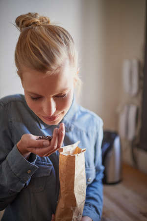 Fresh aroma of coffee beans. A young woman smelling fresh coffee beans in her kitchen.の写真素材