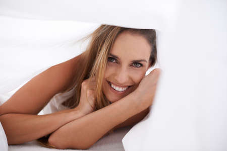 I think Im just going to stay right here.... Portrait of a beautiful young woman enjoying a morning in bed.の写真素材