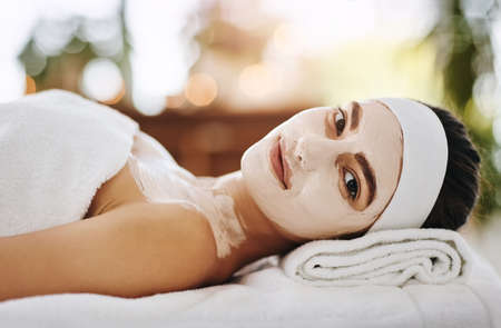 Who doesnt love days like these. Shot of an attractive young woman getting a facial at a beauty spa.の写真素材