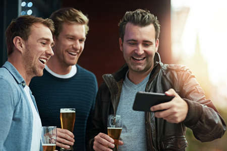 Check out this video. Shot of a group of friends enjoying a beer together while standing on a balcony together.の写真素材