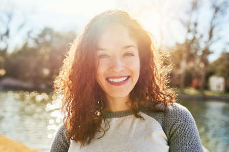 The summer sun is why I love the outdoors. Portrait of a beautiful young woman standing next to a...