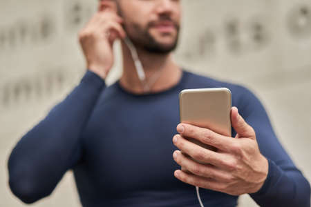 Fully loaded with the best workout tracks. Cropped shot of an unrecognizable male runner adjusting...