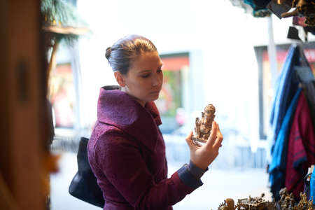 Picking up some souvenirs. Cropped shot of a female tourist holding a souvenir while browsing a...