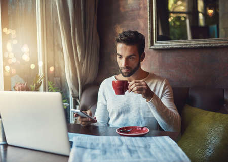 Starting his weekend off right. Cropped shot of a young man drinking coffee in a local cafe.の写真素材