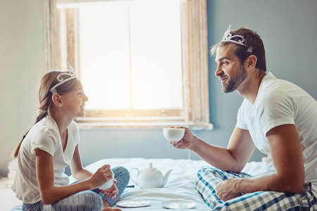 He knows just how to make her smile. Shot of a father and daughter having a tea party at home.の写真素材