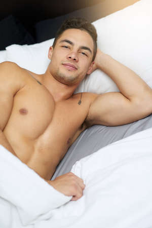Im good in bed, I can sleep for days. Cropped shot of a handsome young man lying in bed.の写真素材