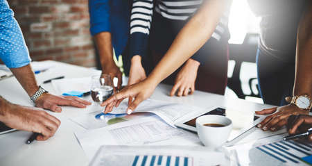 On a mission to solve the right solutions. Cropped shot of a group of businesspeople going through...