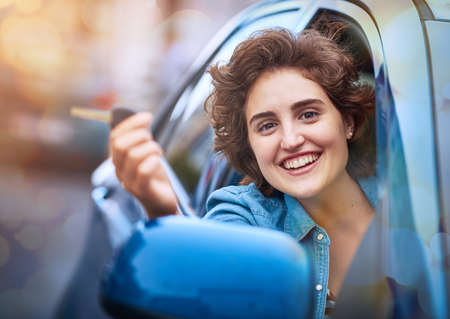 Life is a journey and you hold the keys. Shot of a happy young woman holding the keys to a new car.の写真素材