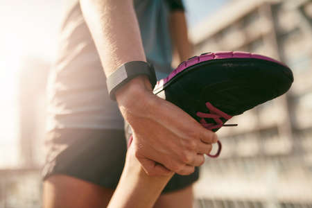 Stretch it out. Rearview shot of a sporty young woman stretching before a run.
