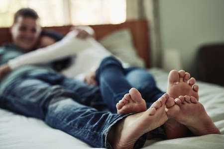 My feet is most comfortable next to yours. Shot of a couples feet as they lay on bed.
