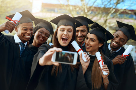 Working world, here we come. Shot of a group of students taking selfies with a mobile phone on...