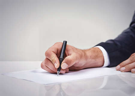 Planning his business day. Cropped shot of a businessman writing on a notepad.の写真素材