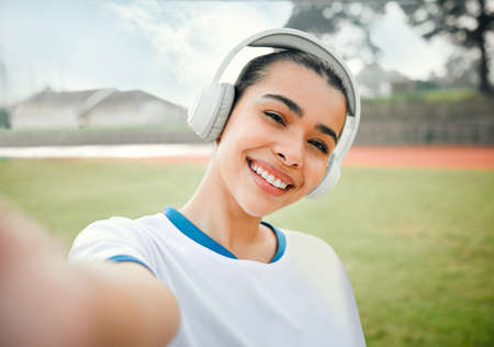 Selfies on the sports field. Cropped portrait of an attractive young female athlete taking selfies while standing outside on a sports field and listening to music.の写真素材