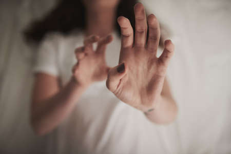 First do no harm. High angle shot of an unidentifiable young woman holding up her hands in a...