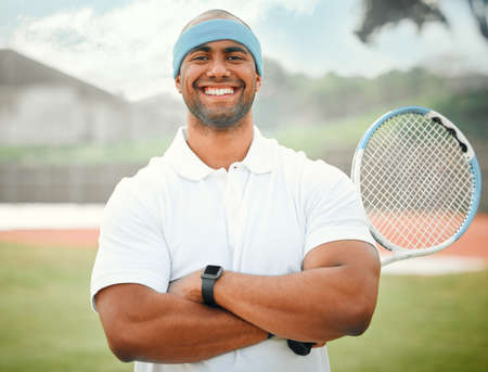 Ready to serve up some competition. Cropped portrait of a handsome young male tennis player standing outside with his arms folded.の写真素材