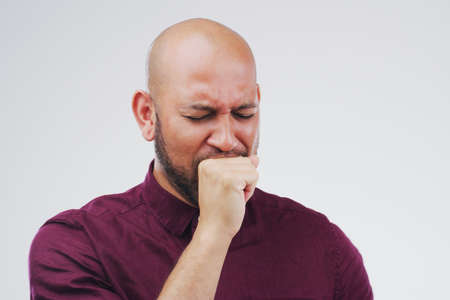 Bronchitis is not the best. Studio shot of a handsome young man coughing against a grey background.