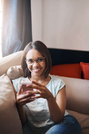 Texting and relaxing. Cropped shot of an attractive young woman using a cellphone at home.の写真素材