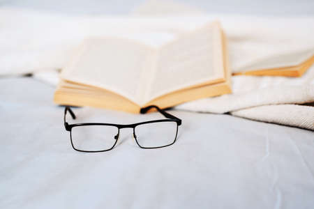 A good read starts with good reading glasses. Still life shot of reading glasses and books lying on a bed.の写真素材