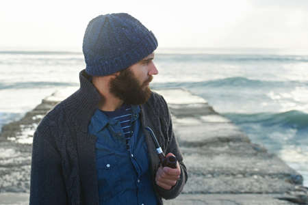 Smoking a pipe. Cropped shot of a bearded man smoking a pipe outside.