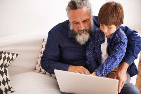 This button switches it on. Shot of a grandfather and grandson using a laptop together.
