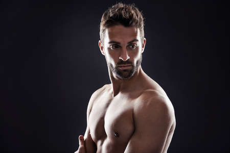 The beard is always a bonus. Studio shot of a handsome man standing shirtless against a black background.の写真素材