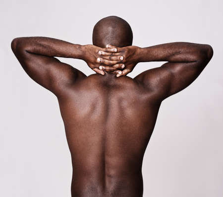 Back to muscle basics. Rearview shot of a muscular african american man holding his hands behind his neck.の写真素材