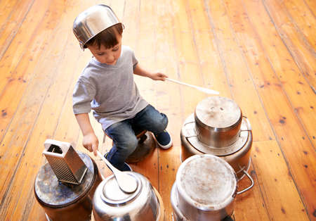 Kids rock. Shot of an adorable little boy drumming on pots and pans.の写真素材