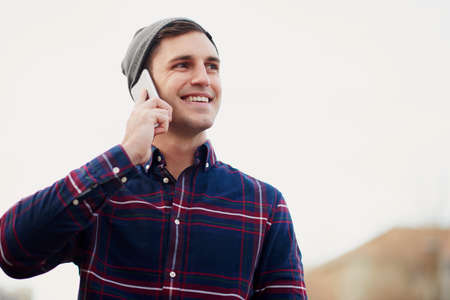 Im on my way into town. Shot of a handsome young man talking on his cellphone while walking through the city.の写真素材