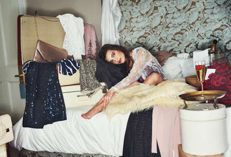 I like to spoil myself here and there. Portrait of a beautiful young woman relaxing on her bed while being surrounded by gifts that she bought herself.の写真素材